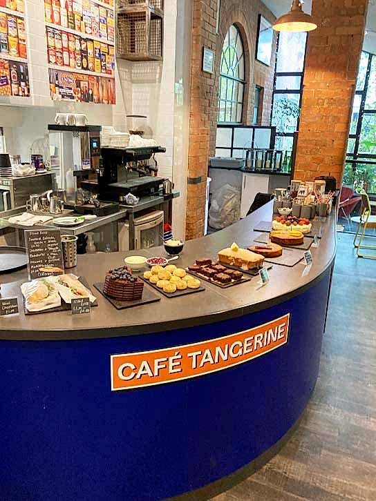 A rounded cafe counter with food laid out, and the words 'Cafe Tangerine' at the front